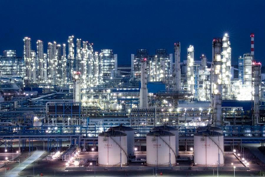 Night-time coal to liquid processing facility with illuminated towers and storage tanks.