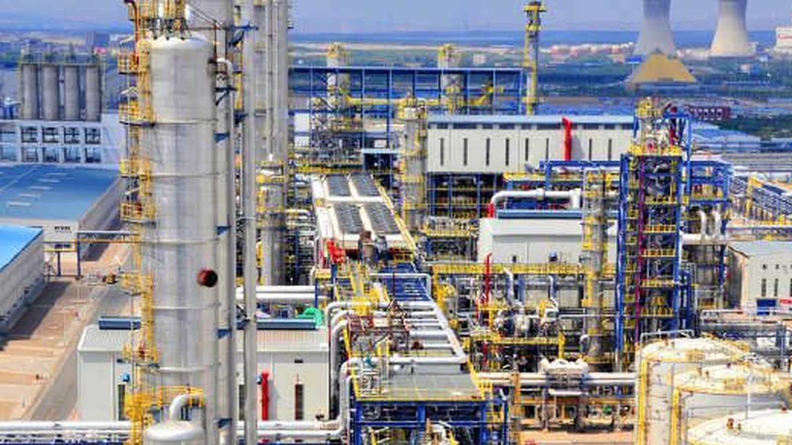 Industrial processing plant with towers, pipe racks and cooling infrastructure.