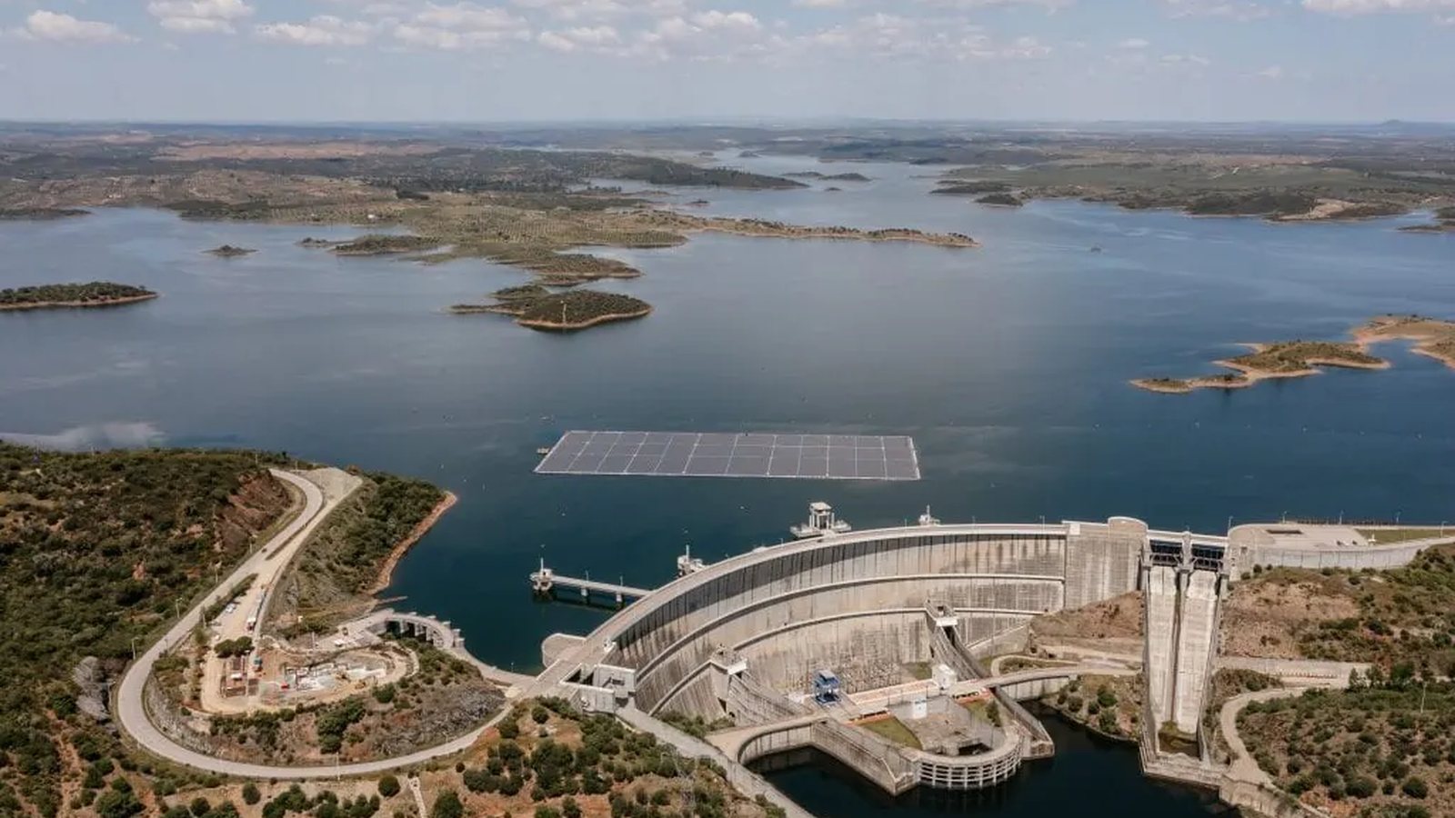 Floating solar installation on a dam reservoir beside hydro infrastructure.